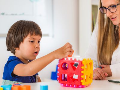 female therapist with a boy playing at table