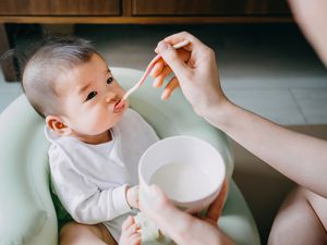 母亲第一次在家里用固体食物喂婴儿——库存照片