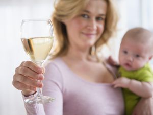 模特摆出母亲抱着婴儿和一杯酒的姿势