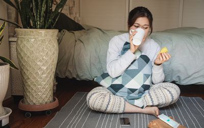 Woman holding a menstrual cup while drinking water in her bedroom