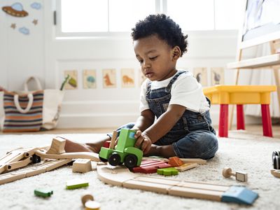 Toddler playing with a wooden toy train on the floor