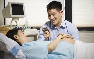 “男人和孕妇坐在一起，手里拿着秒表，微笑着”