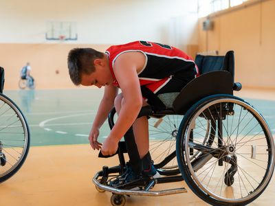Boy sits in a wheelchair and prepares for basketball game