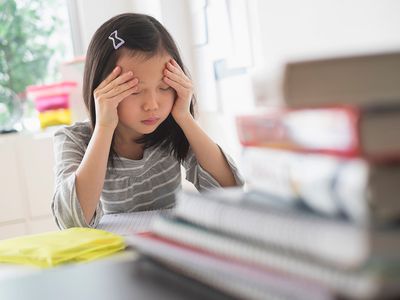 Anxious Chinese student rubbing forehead doing homework