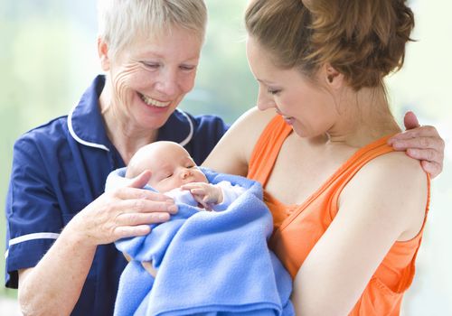 Proud grandmother watches daughter holding newborn grandson