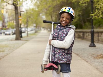 Girl on sidewalk carrying scooter