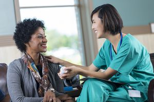 Friendly Asian nurse or doctor giving medication to patient