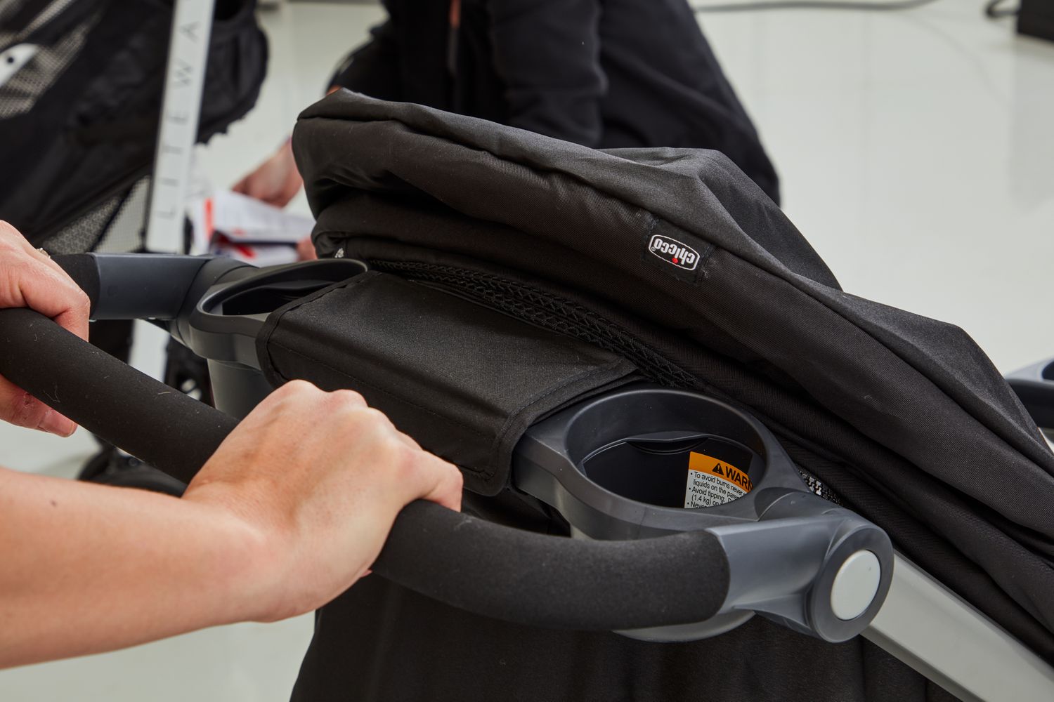 Person holding the handle of Chicco Bravo Trio Travel System