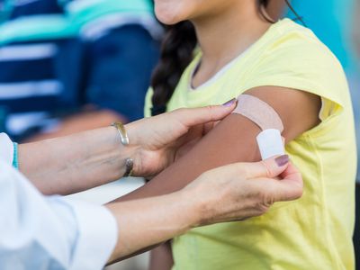 Doctor applies bandage to preteen girl's arm following an immunization