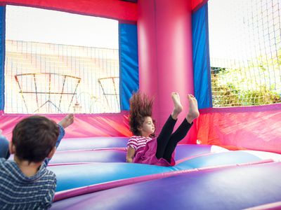 Siblings playing in bouncy castle at backyard