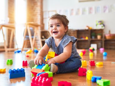 toddler sitting on the floor playing with building blocks