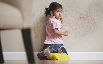 little girl drawing on the wall