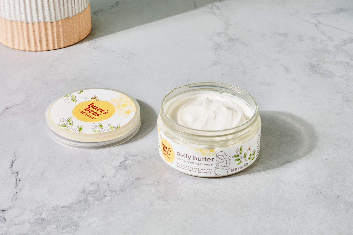 Burt's Bees Mama Belly Butter with Shea Butter and Vitamin E placed on grey floor