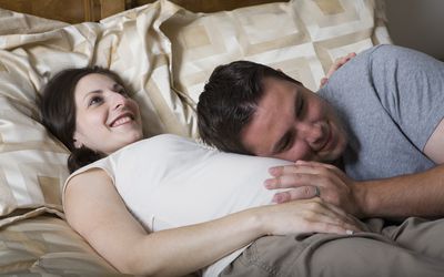 伴侣抱着妈妈怀孕的腹部
