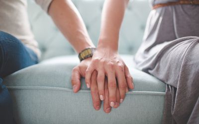 男人和女人手牵着手坐在沙发上的照片