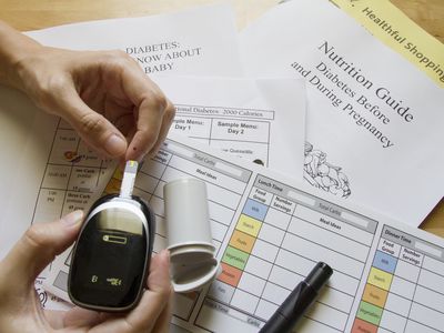 close up of a woman's hands using a blood sugar monitoring device