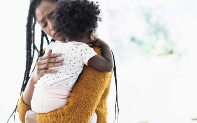 Woman holding and comforting baby daughter
