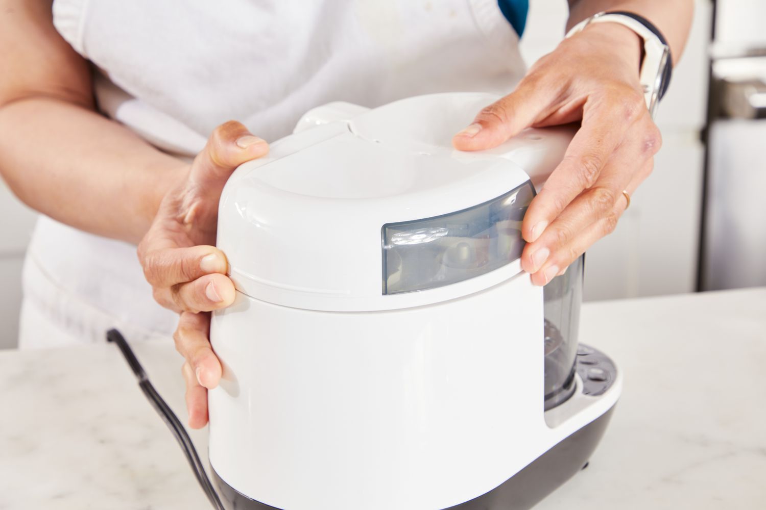 A person secures the Baby Brezza One Step Glass Baby Food Maker.