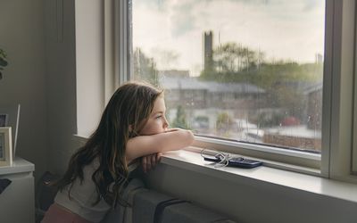 一个小女孩在雨天看着窗外