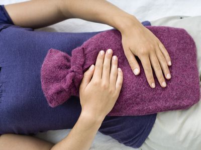 Young woman holding a hot water bottle on her stomach