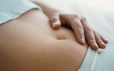 手放在女人的腹部，因为排卵过多而感到肿胀和敏感