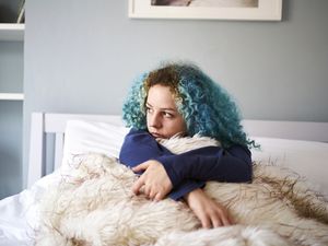 年轻女子独自躺在床上，看上去很悲伤