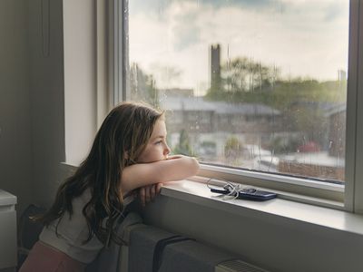 young girl looking out the window on a rainy day