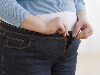 Person buttoning their maternity jeans