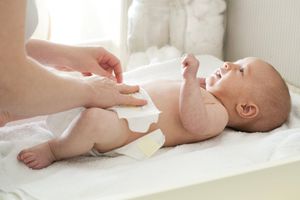 母亲正在给婴儿换尿布＂width=