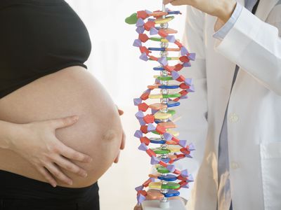 Pregnant woman and doctor examining DNA model