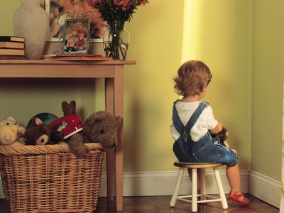 Young child sitting in corner as punishment
