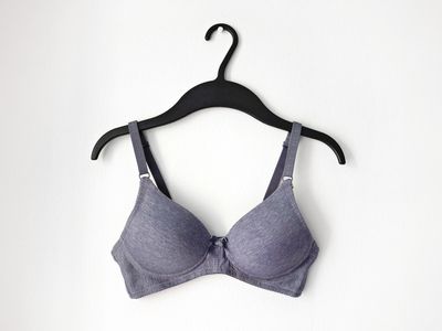 Close-Up Of Bra Hanging On Coathanger Against White Wall