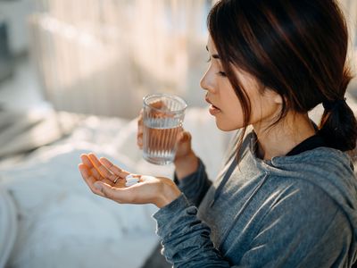 Woman holding pills in her hand about to take them