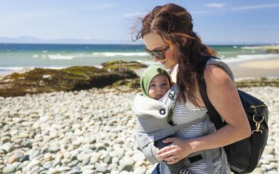 Mother with baby son in carrier at beach