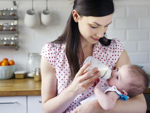 母亲在家用奶瓶喂婴儿。