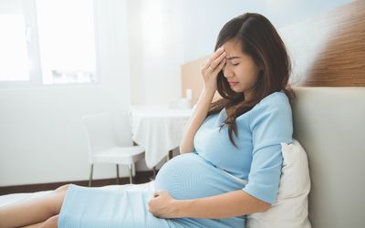 头痛的孕妇坐在床上
