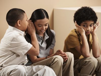 Three children (7-10), boy whispering to girl