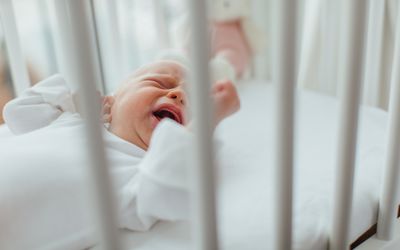 Baby girl lying in crib crying