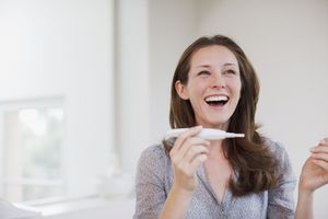 微笑的妇女拿着怀孕测试呈阳性华体会体育官方人口