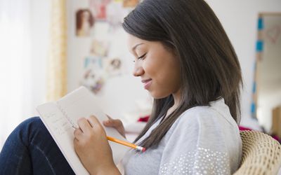 Smiling teenage girl writing in a journal