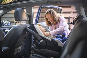 Mother putting her son in a car safety seat
