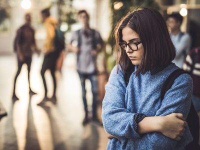 teen girl looking sad in a school hallway