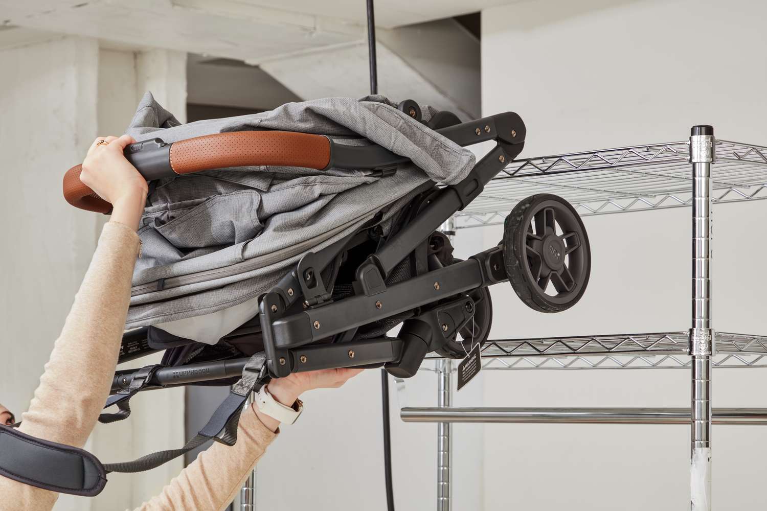 Hand stows the Uppababy Minu V2 stroller on a high shelf.