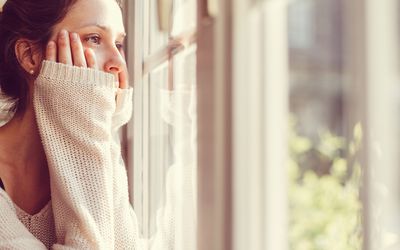 穿白色毛衣的女人看着窗外。