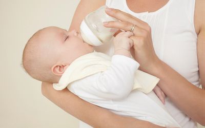 Mother feeding newborn baby bottle of baby milk