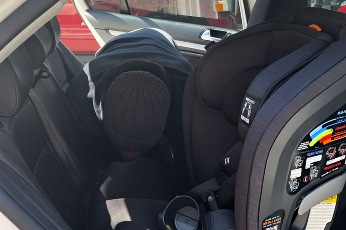 Person installing the Chicco OneFit ClearTex All-in-One Car Seat in their car