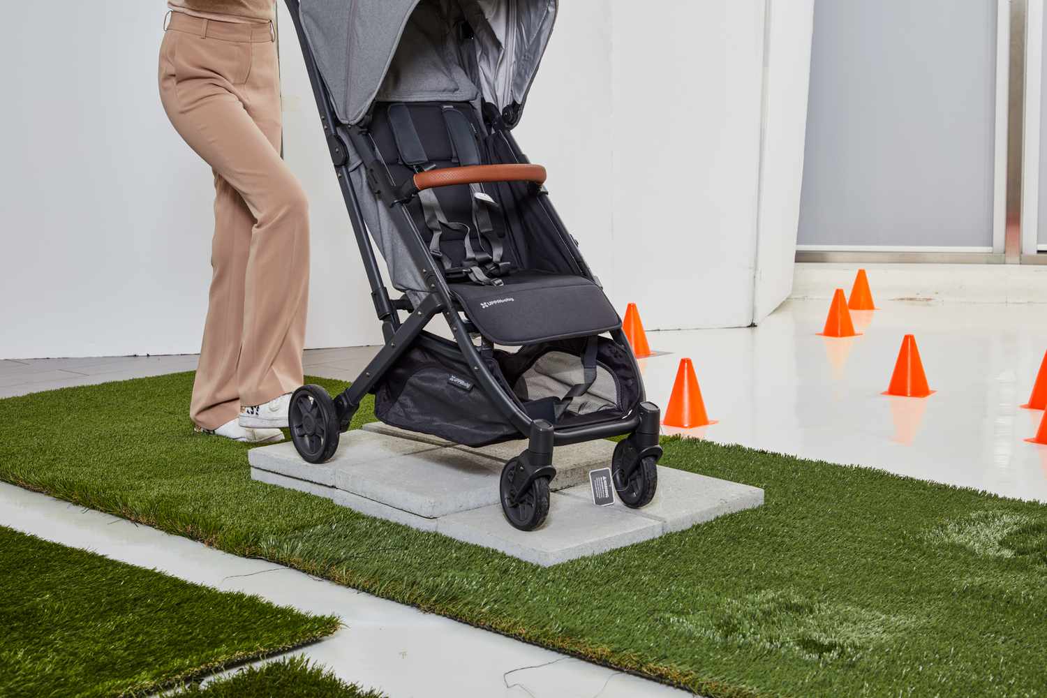 Person testing Uppababy Minu V2 on stone floor above grass mat