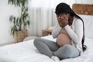 孕妇坐在床上，可怜的女人
