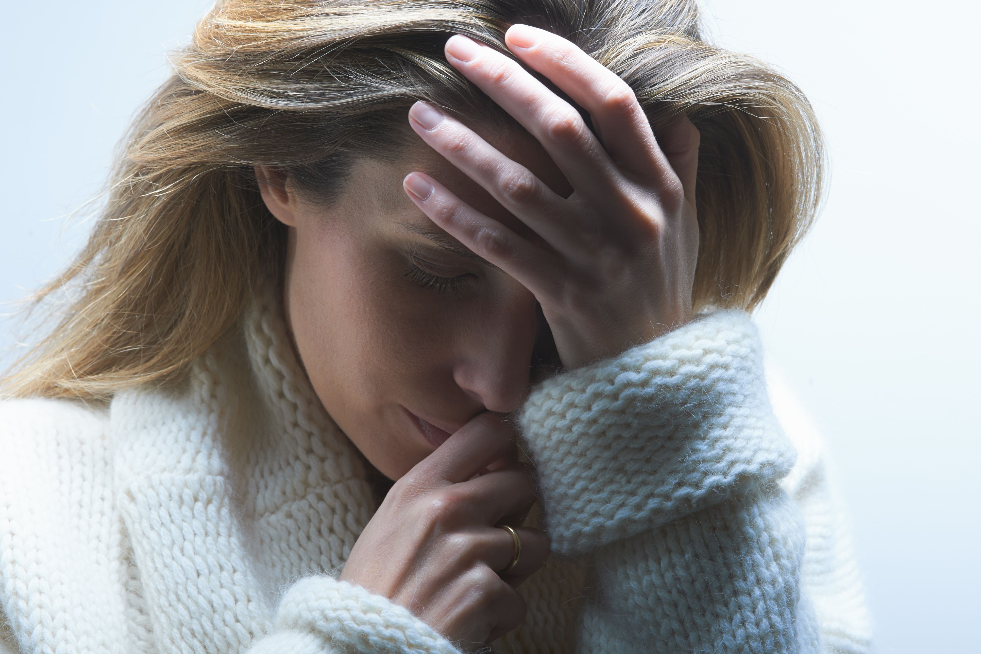 穿着毛衣的女人抱着头，因为不孕而感到沮丧和焦虑