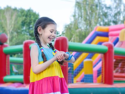 Cute beautiful little girl with a smile on her face talking on a smart watch on the street.Safety concept